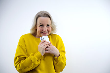 cute woman plotting something holding a phone in her hands wants to call someone smiling secret...