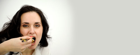 banner beautiful brunette eating sushi with chopsticks close-up face open mouth eyes narrowed with pleasure space for text sushi lunch tasty healthy japanese food rest enjoyの写真素材