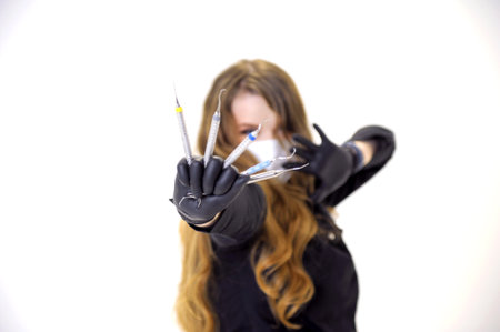 Beautiful woman dentist in a black suit with a white mask with flowing hair holds in her hands...