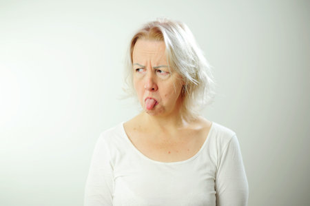 Dont come near me Im offended Adult woman with white hair is offended She shows her tongue expressively Her eyebrows are shifted, she is puffed up and does not want to talk to anyone.の写真素材