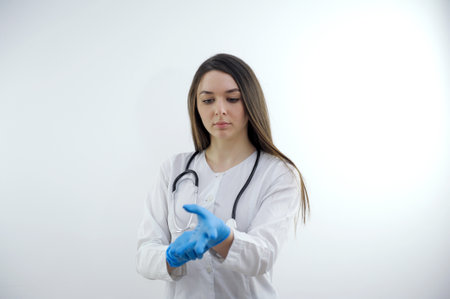 Beautiful Doctor Nurse woman in uniform with stethoscope, wearing rubber gloves act pose, oxygen mask in Medical hospital, portrait black hair, studio lighting blue background copy spaceの写真素材