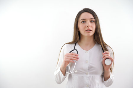 Beautiful young African American nurse or doctor with stethoscope stands, looking to the right side wearing blue scrubs and long curly hairの写真素材