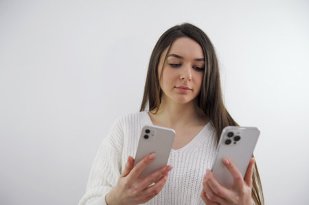 a young girl compares two phones with cameras on one or two cameras on the second three cameras the latest technology photography video filming choose a phoneの写真素材