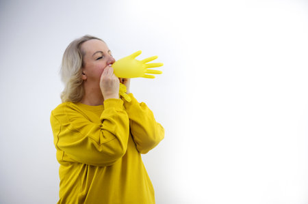 woman in yellow puts on a bright yellow glove on a white background deception swindle concept relived for the patientの写真素材