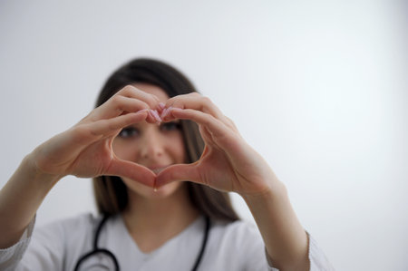 Close up of two female caucasian hands isolated on white background. Young woman forming shape of heart with her fingers. Horizontal color photography. Point of view shotの写真素材