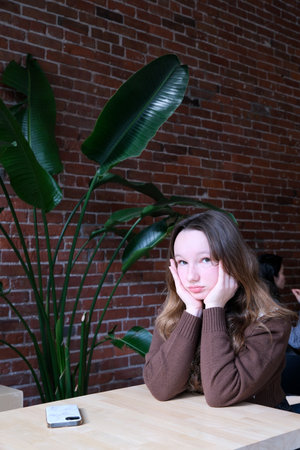 Upset young girl sitting alone in cafe offended at friends joke, sad millennial woman suffer from low self-esteem, depressed female outcast feeling outsider hanging out with company in coffeeshopの写真素材