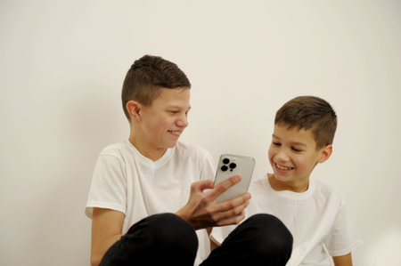 Two young Asian brother compete on smartphone to play on white backgroundの写真素材