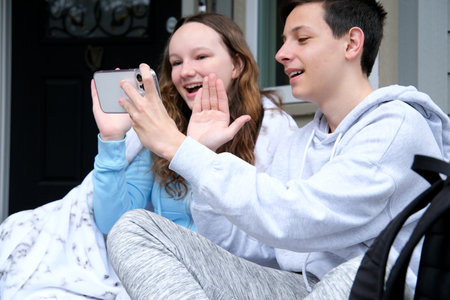 Beautiful young couple relaxing on a couch at home, using laptop computer, taking a selfie