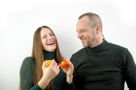 Happy laughing couple kissing in slowmo talking and peeling tangerines. Pregnant Caucasian wife and...