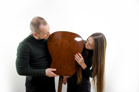 man and woman fooling around with a guitar turned it upside down talking leaning their chin on a...