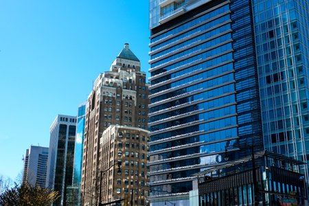 beautiful glass buildings skyscrapers rising into the blue sky without clouds Vancouver cherry blossoms in spring the camera slowly captures the cityscape office buildings the latest technologyのeditorial素材