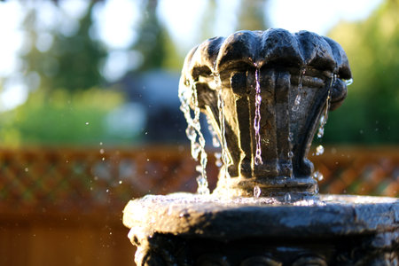 Defocused drops of water from a fountain at the setting sun. Slow motion. Drops of water in the air of the fountain, defocused bokeh.の写真素材
