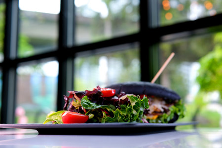 Black bun burger served at table appetizing black burger with salad stands on the table delicious...