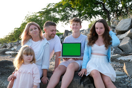 big family mom dad and three children hands of a laptop with a place for advertising text sit on the rocks travel relaxation rest interesting films the latest technology wireless communicationの写真素材