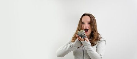 a young girl straightens her hair stands on a white background in sportswear in her hands she holds...