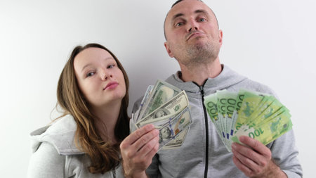 father and daughter a lot of money in their hands joy success dollars euro 100 dollar bill wave money like a fan look into the frame make faces confidence success big win purchase giftの写真素材
