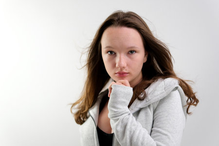 Girl with long blonde hair in white shirt poses in studio on white background. Model tests. Lovely girl with delicate facial features, tedious makeup. Wind is blowing hair.の写真素材