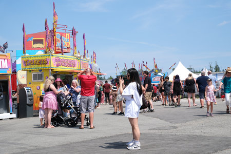 amusement park adults and children stroll against backdrop of swing. people have fun on summer autumn day. teenagers buy tickets spend time with family. large crowd of american people on holidayのeditorial素材