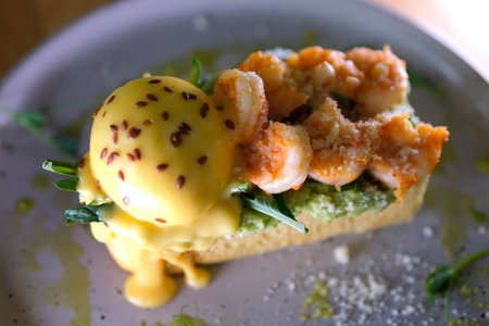 breakfast toast with avocado and egg shrimp Parmesan greens appetizing aromatic lunch snack sprinkled with flax grains seeds on gray plate restaurant serving dipping shrimp egg yolk several videosの写真素材