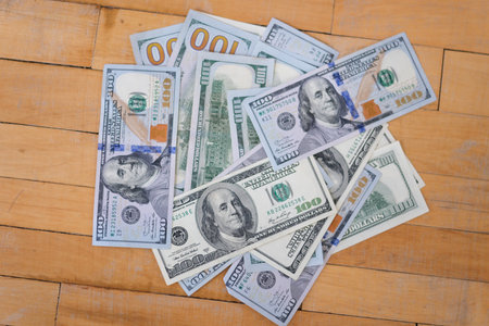 Many different dollar bills lying on wooden table closeup background