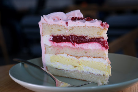 Eating cheesecake with a fork. Taking bite of cheesecake. Sweet dessert food Close up of a pink strawberry cake swirling on a white plate.の写真素材