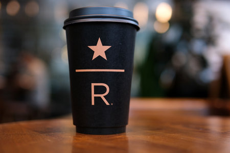 Starbucks Resort black Starbucks cup with star underline big letter R on the table in the coffee...