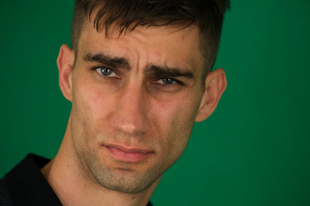 the anxious look of a handsome young man on a green background chromakey blue eyes light stubble...