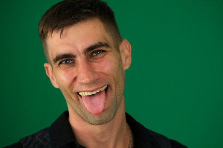 Happy man showing his tongue on white background, closeupの写真素材