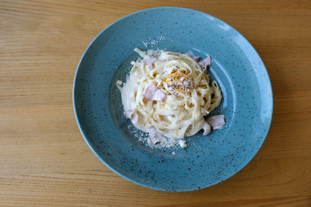 Homemade Carbonara pasta Pasta carbonara with parmesan cheese in clay plate isolated on black backgroundの写真素材
