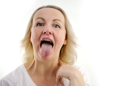 a woman shows her tongue healthy clean tongue Female tongue with a white coating. isolated on white background. Gastrointestinal disease, organ dysfunction, poor oral hygiene, fungal infectionsの写真素材