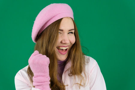 Attractive red haired girl, stares in surprise and points her hands up to the free space on an isolated backgroundの写真素材