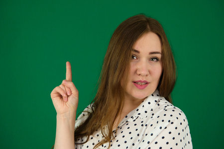 Studio shot of young overweight beautiful woman. Pretty woman smiling with happy face looking and pointing to the side with finger Isolated on green backgroundの写真素材
