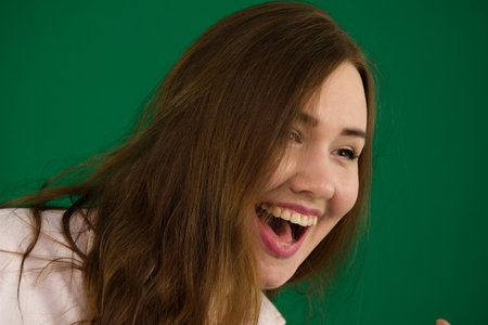 Happy beautiful smiling, laughing young woman. Green background. Long hair.の写真素材