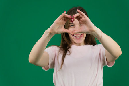 pretty young girl making a heart symbol with her hands, focus on the handsの写真素材