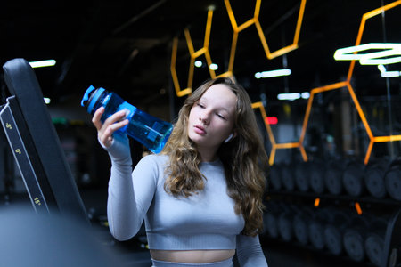 Gym girl drinks water Fit woman runner outdoors holding water bottle. Fitness woman taking a break...