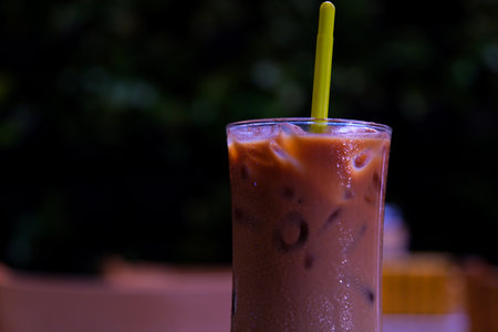 Iced coffee with cream, refreshing and sweet coffee drink on a beige ceramic table.