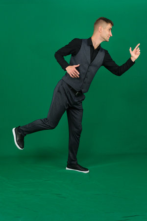 Side view of happy smiling overjoyed handsome man wearing trendy green suit and spectacles dancing...