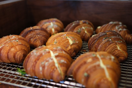 Golden brown croissants are neatly arranged on wooden boards, alongside other pastries like donuts...