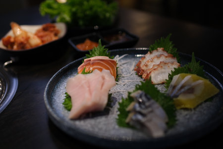 Detailed view of salmon and tuna sashimi artfully arranged on a green leaf with garnish.の写真素材