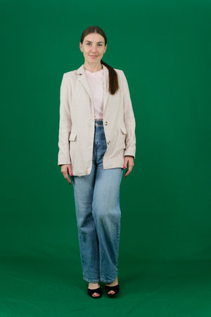 Set of photos of young European woman in light blazer and blue jeans showing various emotions gestures and expressions on green chroma key background with copy space for advertising and social mediaの写真素材