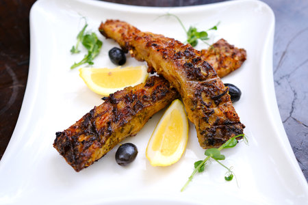 A delicious and beautifully presented dish of two grilled fish, garnished with fresh lettuce,...