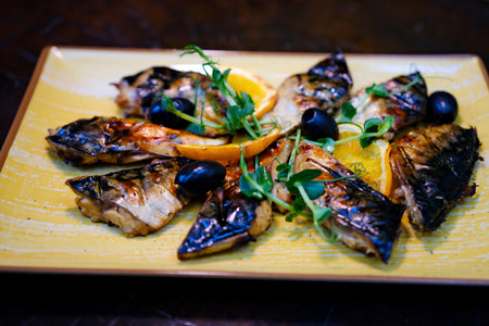 Grilled mackerel fish fillet on a grill. Black background. Top view.