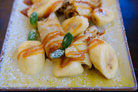 Crepes bananas caramel Crepes stuffed with chocolate spread and banana on white plate. Thin pancakes, blini. Sweet dessert.の写真素材