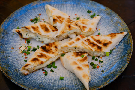 Grilled lavash with cheese on a blue plate, pieces served in a restaurantの写真素材