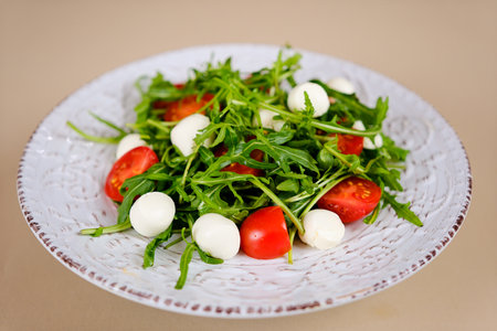 Fresh green salad made with mozzarella cheese, cherry tomatoes, arugula and olive oil on white stone table background. Healthy food and diet concept. Flat lay, copy space.の写真素材