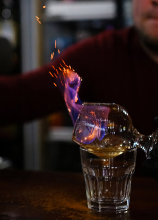 The bartender makes flame over a cocktail with orange peel close upの写真素材