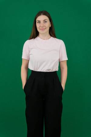 Various emotions of a European woman in a pink T-shirt and black pants on a green background with...