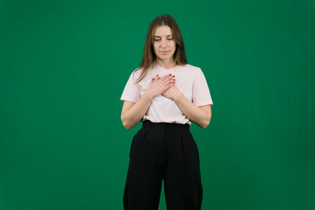 Various emotions of a European woman in a pink T-shirt and black pants on a green background with...