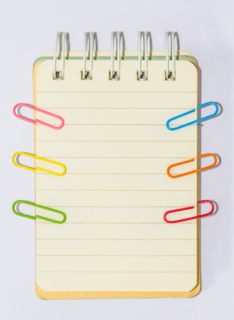 Colorful paperclips and note book on white background isolatedの写真素材