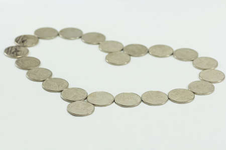 coins in the shape of a heart isolated on white